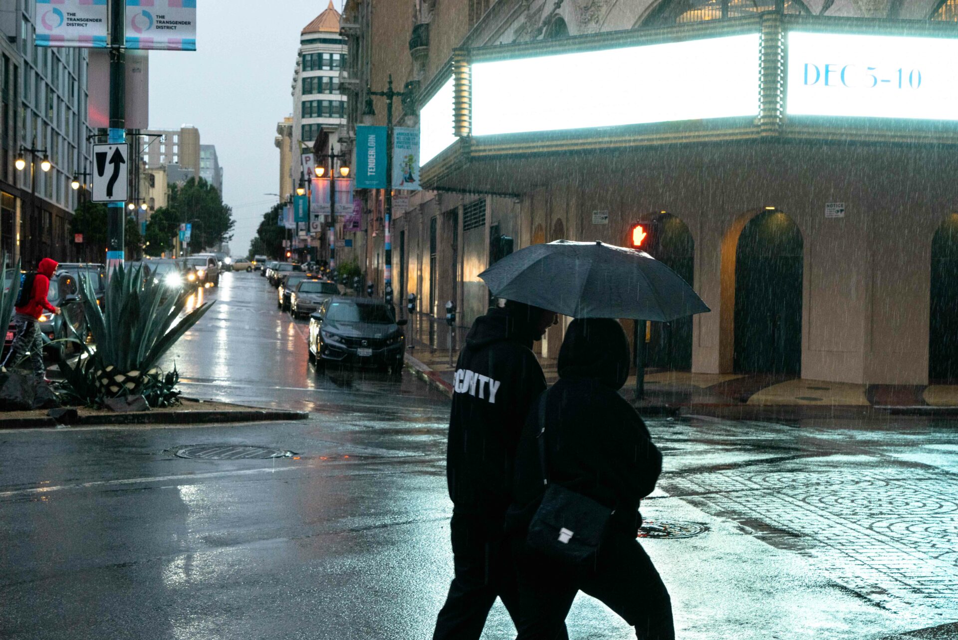November 2023 An off-duty security guard escorts a friend through the empty wet streets of San Francisco during the Asian Pacific Economic Cooperation leaders week November 11-17. To the outside world, the city appeared resilient if glistening from the season’s first rains. But residents felt sidelined by the fortress downtown. Photo: George Alfaro.