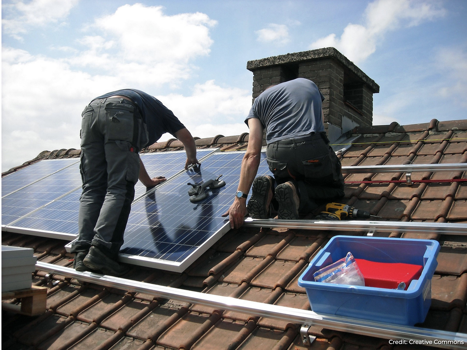 Workmen on roof installing solar panels.