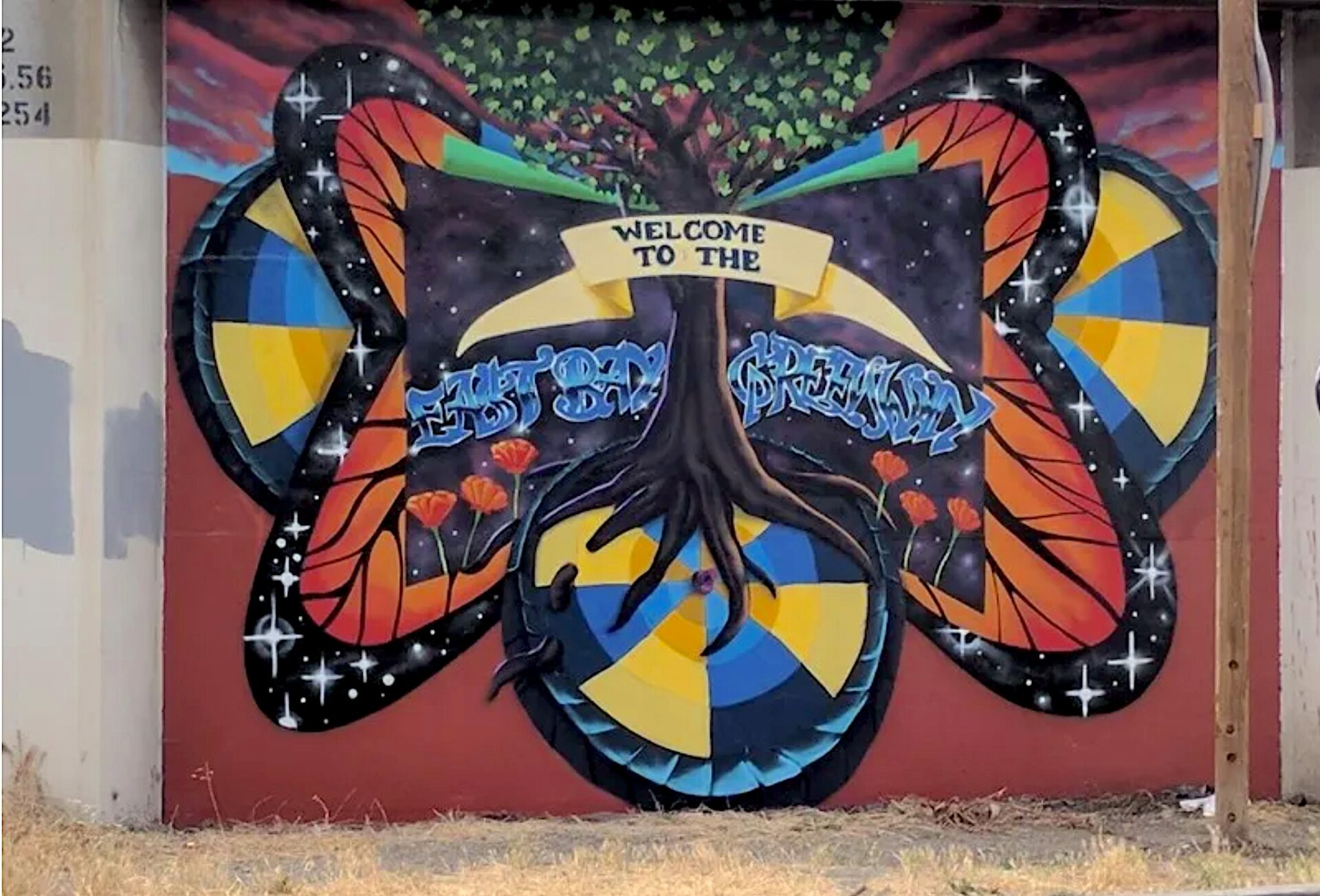 Mural near Coliseum BART signing East Bay Greenway. Art: Scraper Bike Team