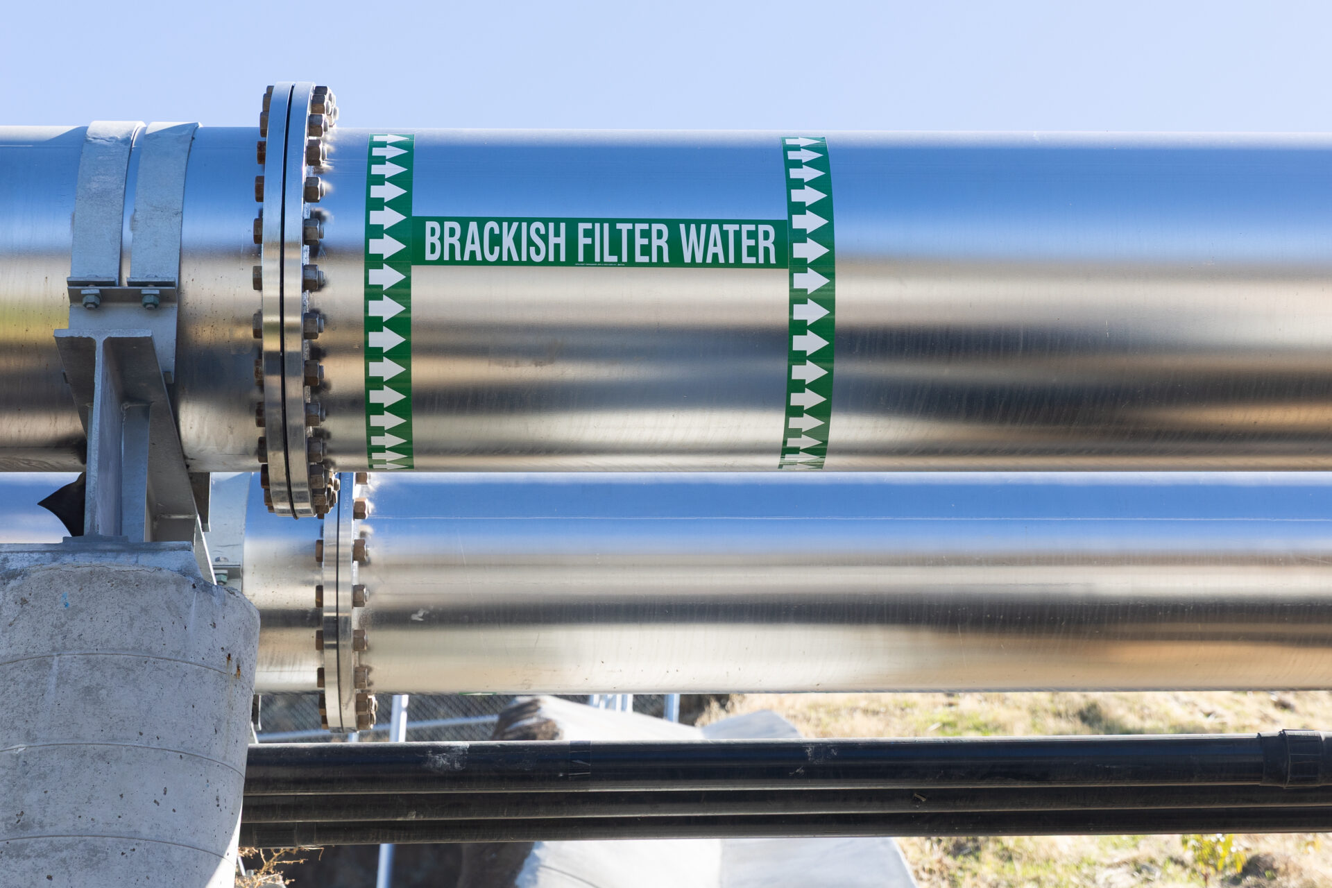 A large silver pipe with green tape marking it for "brackish filter water"