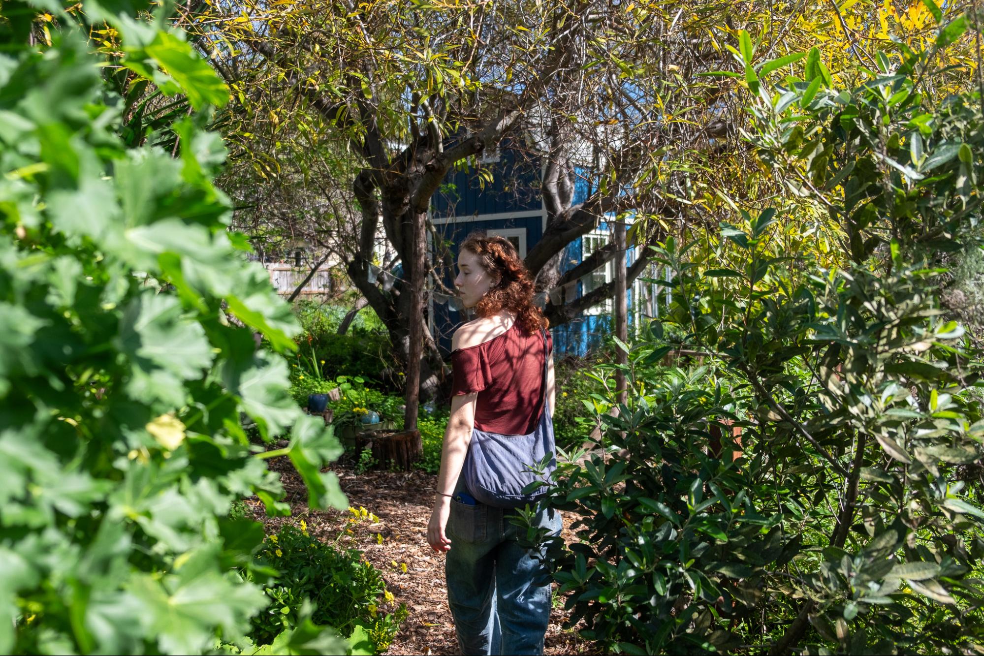 A woman walks through trees.