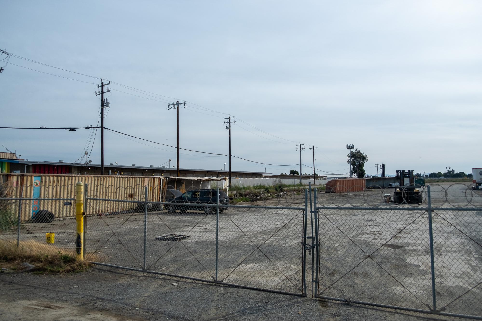 An empty concrete lot behind a fence
