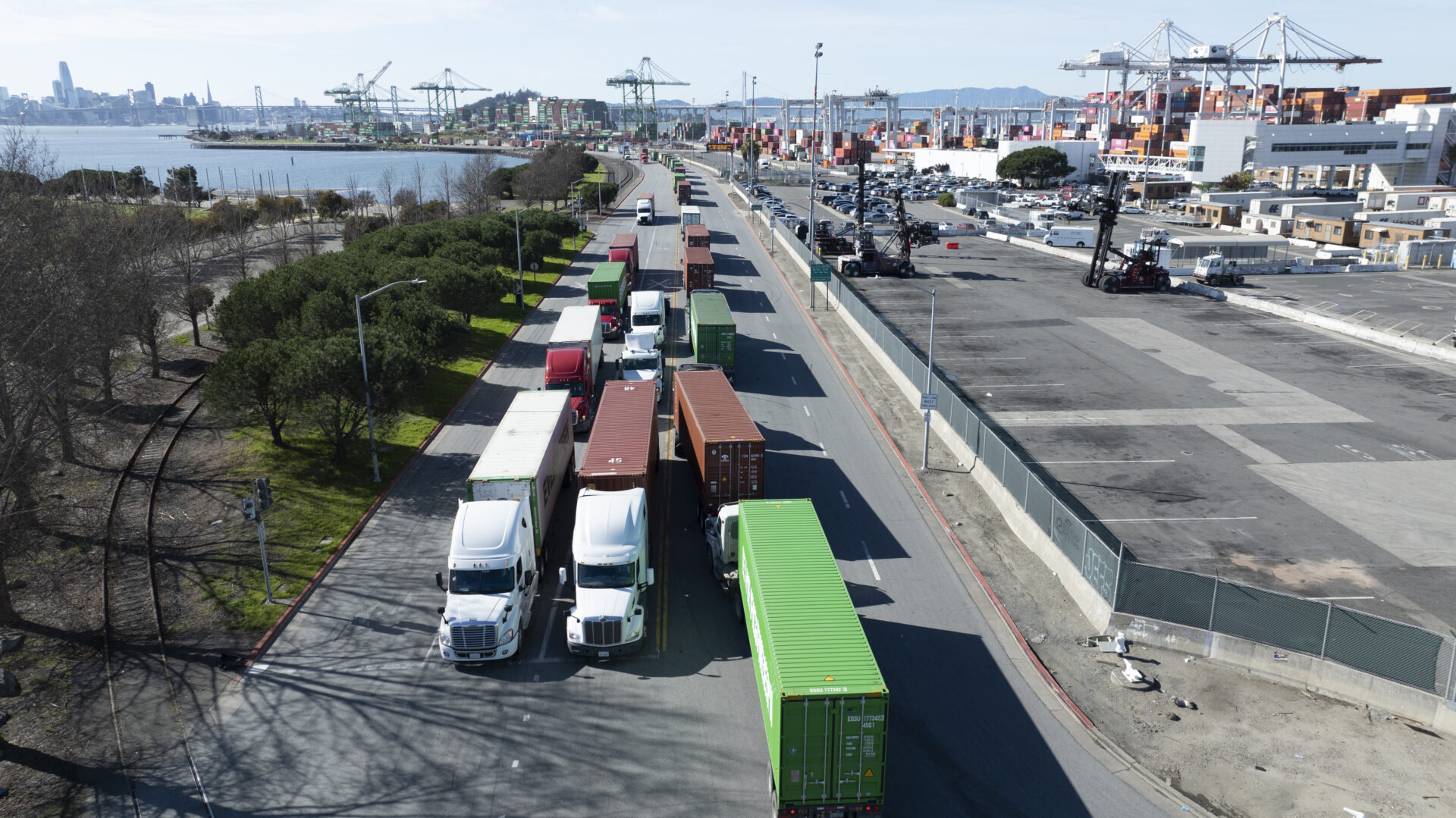 Rows of over a dozen trucks by the Port of Oakland.